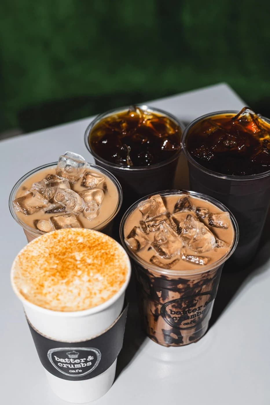 A group of iced coffees and a dusted cappuccino