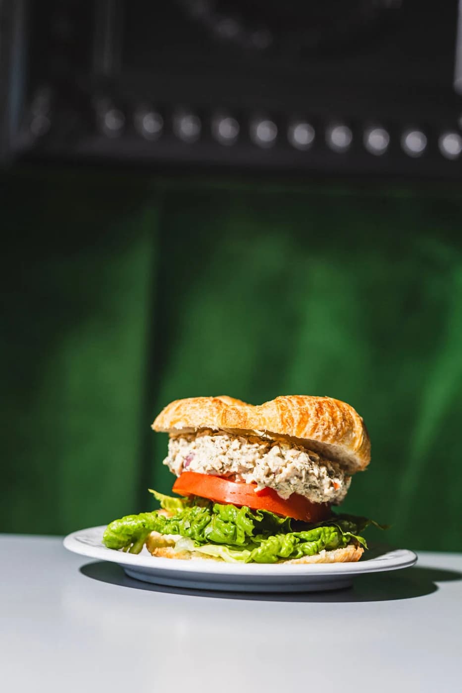 A croissant sandwich with avocado, tomato and chickpea salad